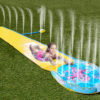 girl enjoying sliding down the water slide with sprinklers and splash zone